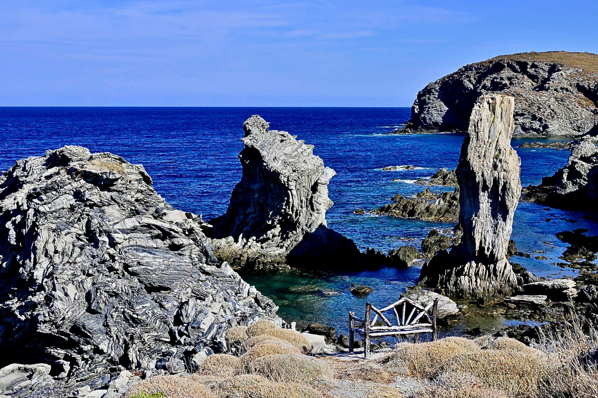 A wooden bench above a cove of rock pillars