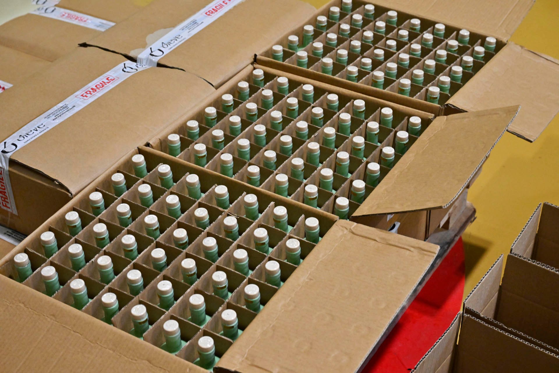 Open cases of mint-green bottles beside sealed ones taped Ol-eve FRAGILE