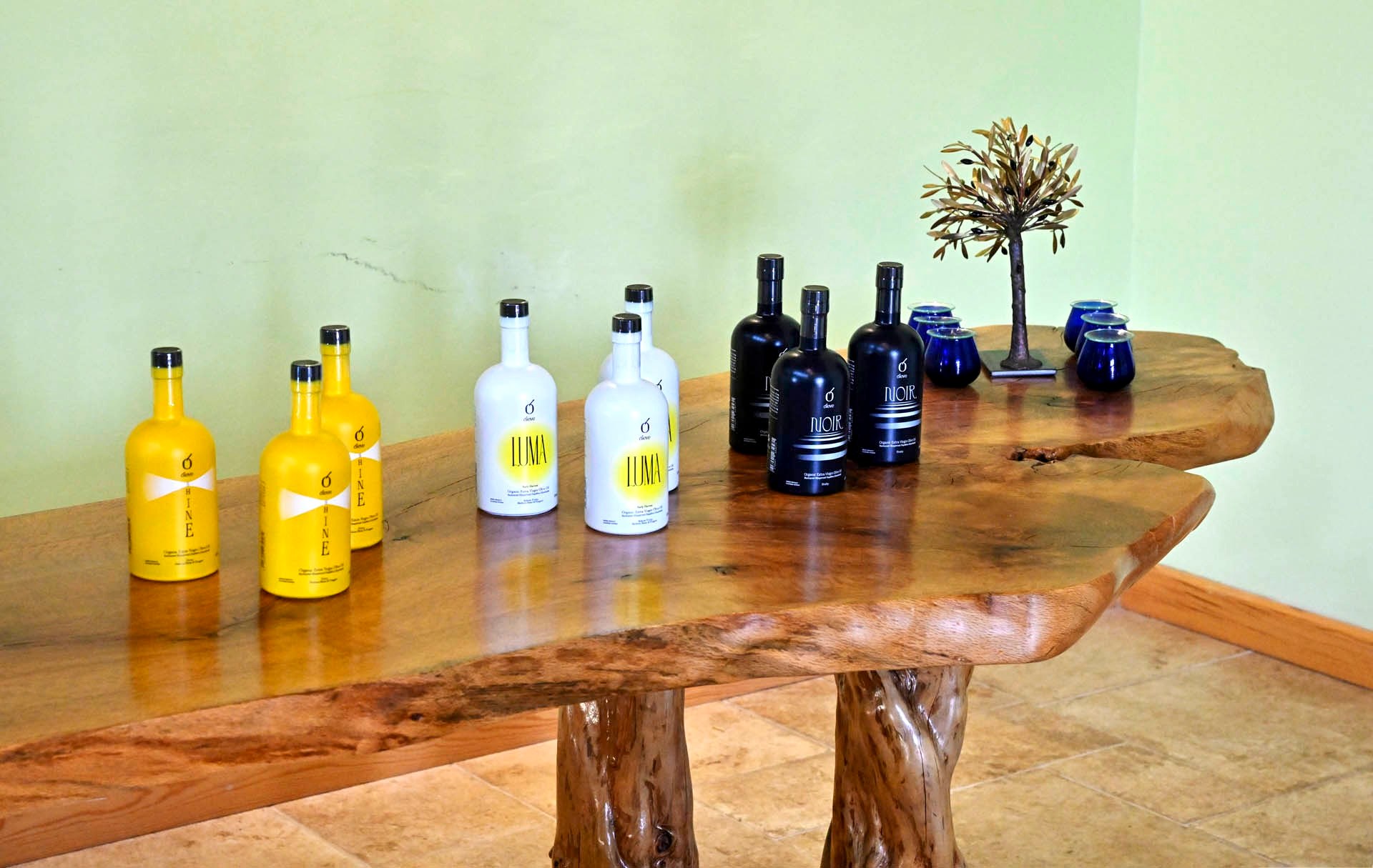 Ol-eve SHINE, LUMA and NOIR on the olive-wood table, the tasting glasses beside them