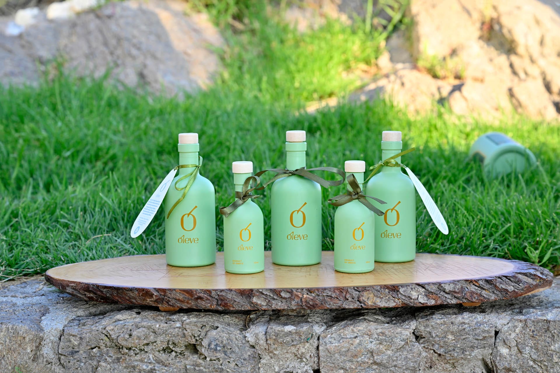 Mint-green Ol-eve bottles in several sizes on a wooden board