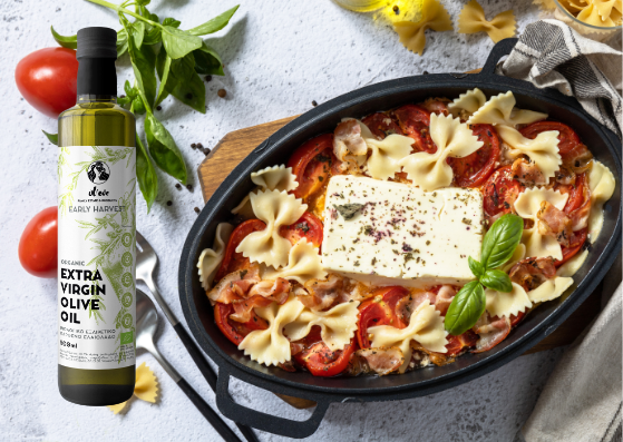 Ulei de măsline Ol-eve Early Harvest lângă o tavă de paste cu feta la cuptor, roșii cherry și busuioc